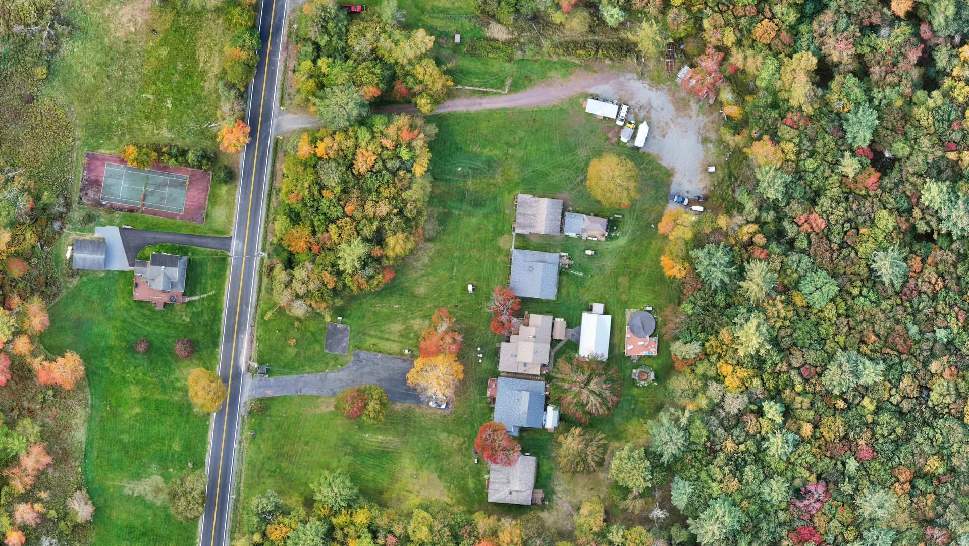Drone orthomosaic showing a road, buildings, lawns and autumn woodland